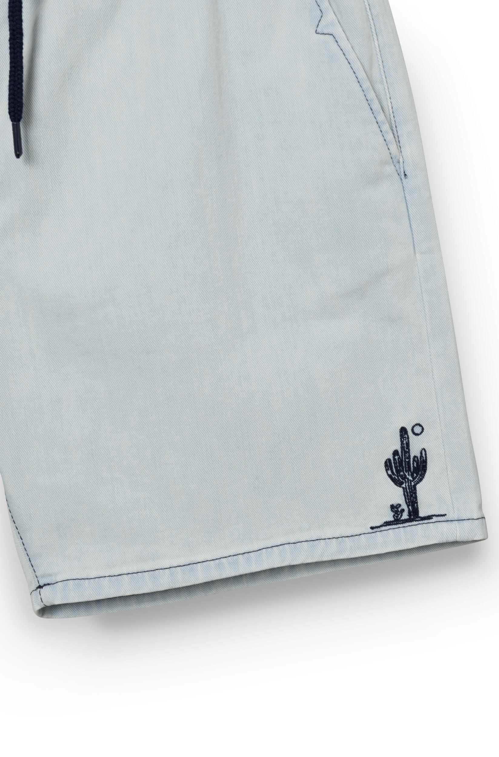 Close-up on the cactus pattern of the faded blue shorts
