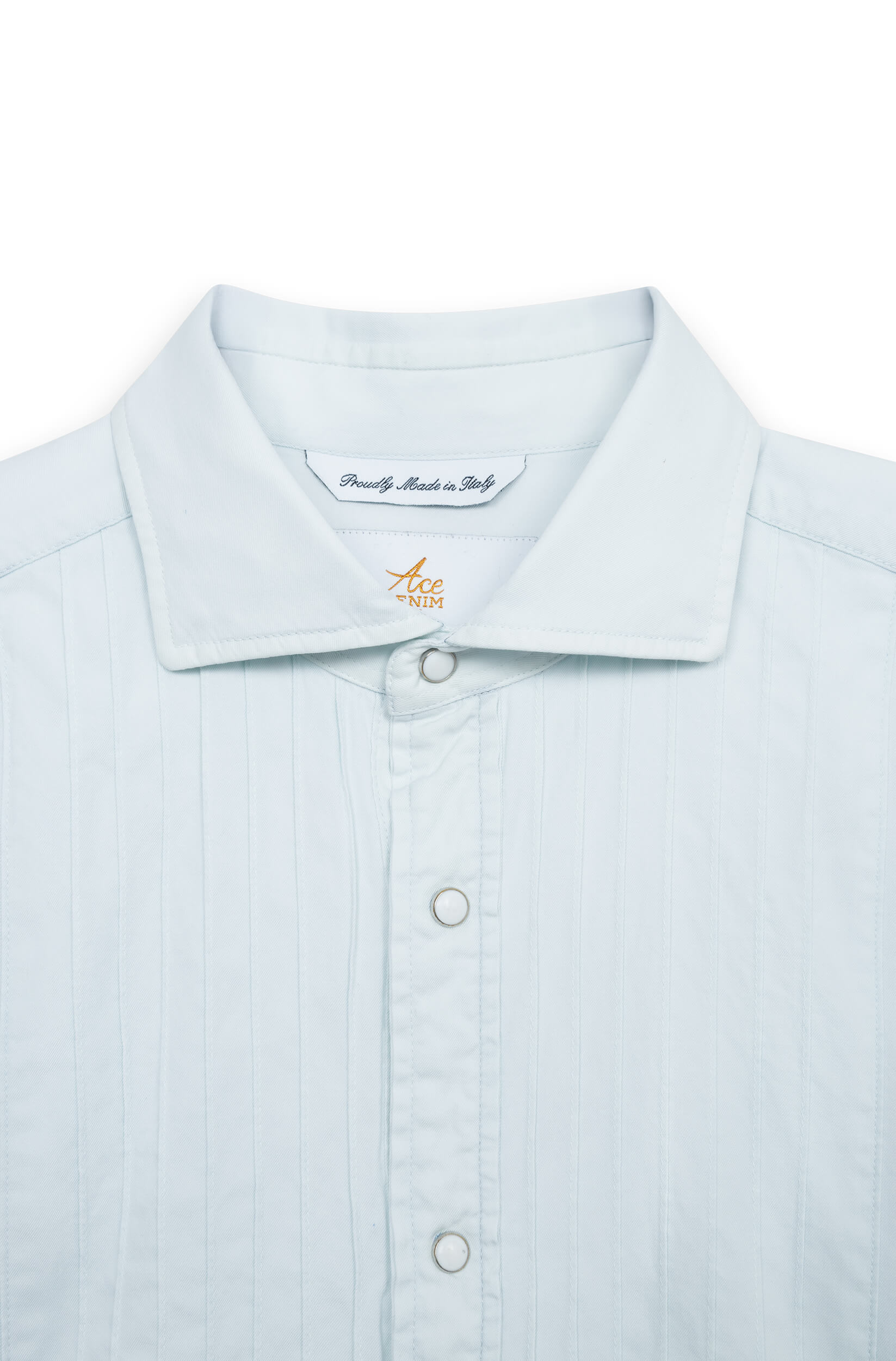 Zoom sur les boutons pressions nacrés et le poignet de la chemise denim délavé.