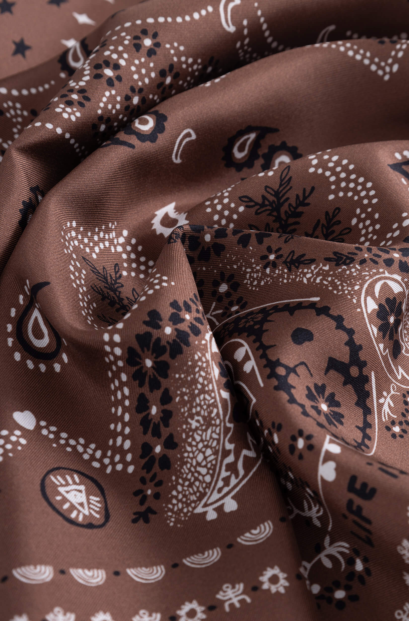 Détail avec texture du foulard en soie marron à motif bandana