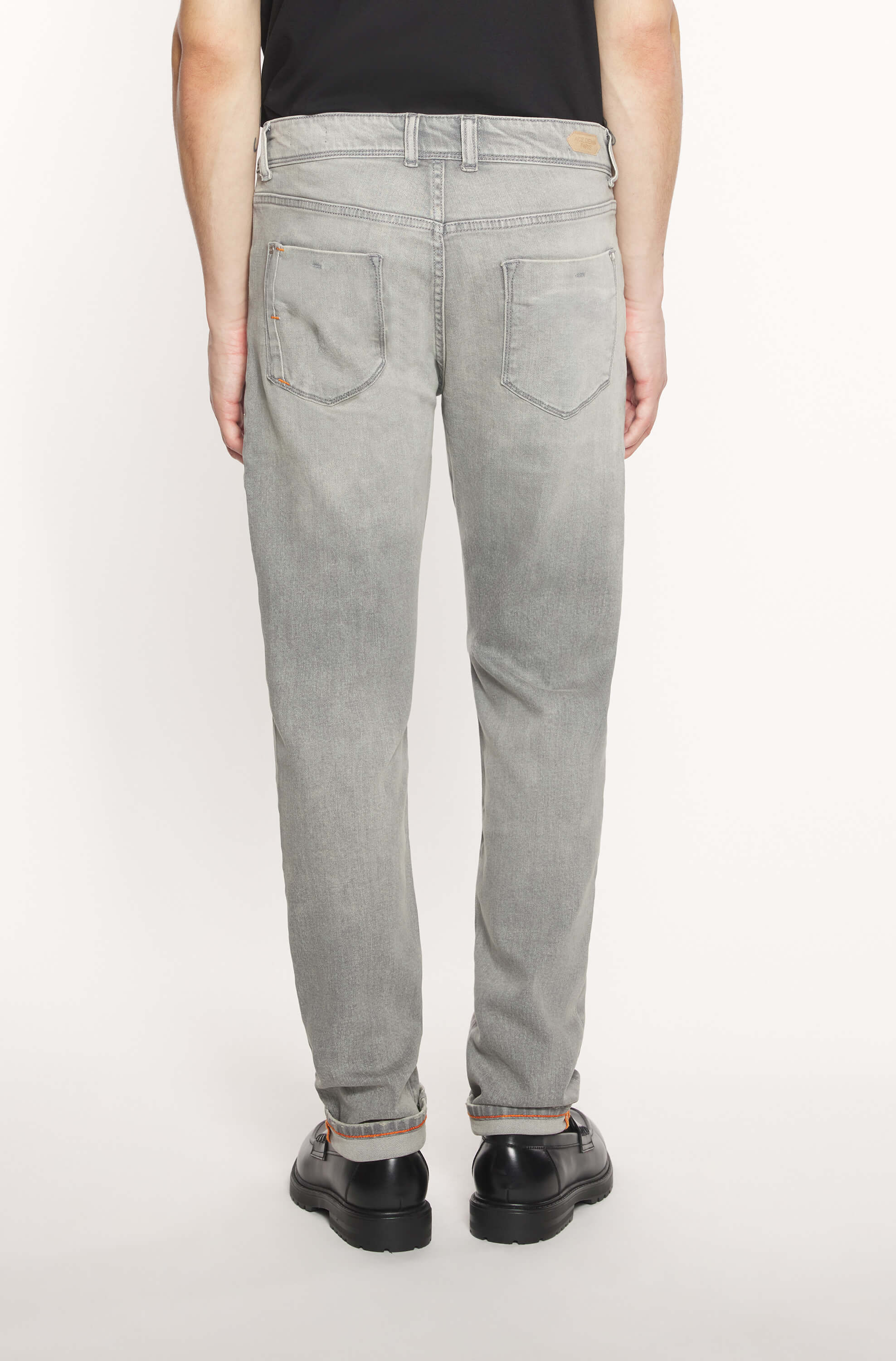 Rear view of the model wearing the light gray AD25 jeans in cashmere