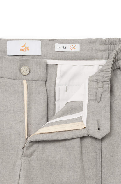 Detail of the front of the light gray trousers with metal button and fly