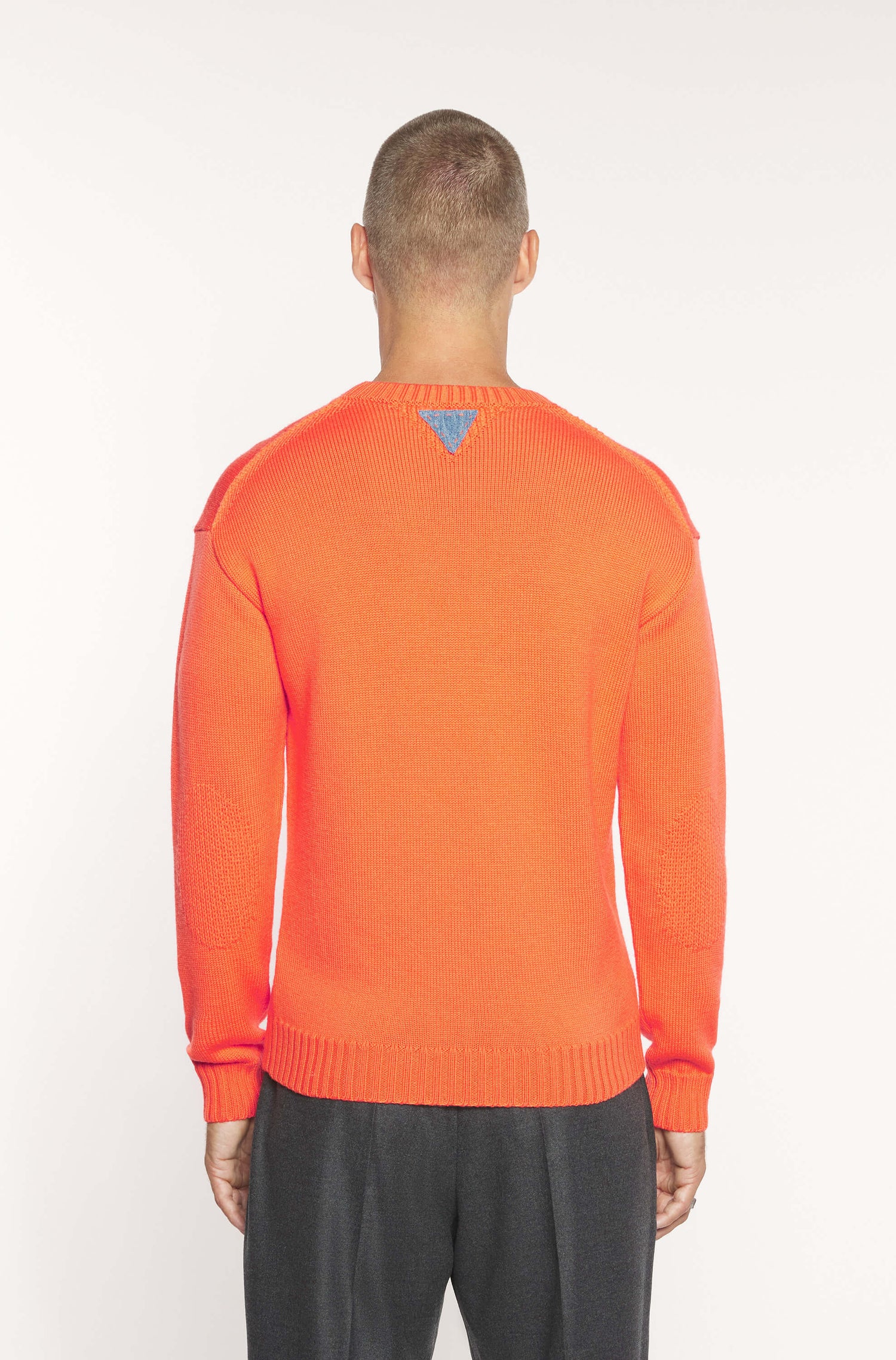 Vue de dos du mannequin portant le pull à col rond orange en laine mérinos
